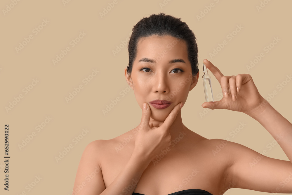 Beautiful Asian woman with ampule on beige background. Skin care concept