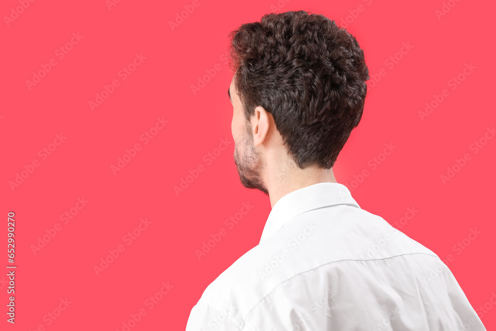 Young brunette man with stylish hairdo on red background, closeup