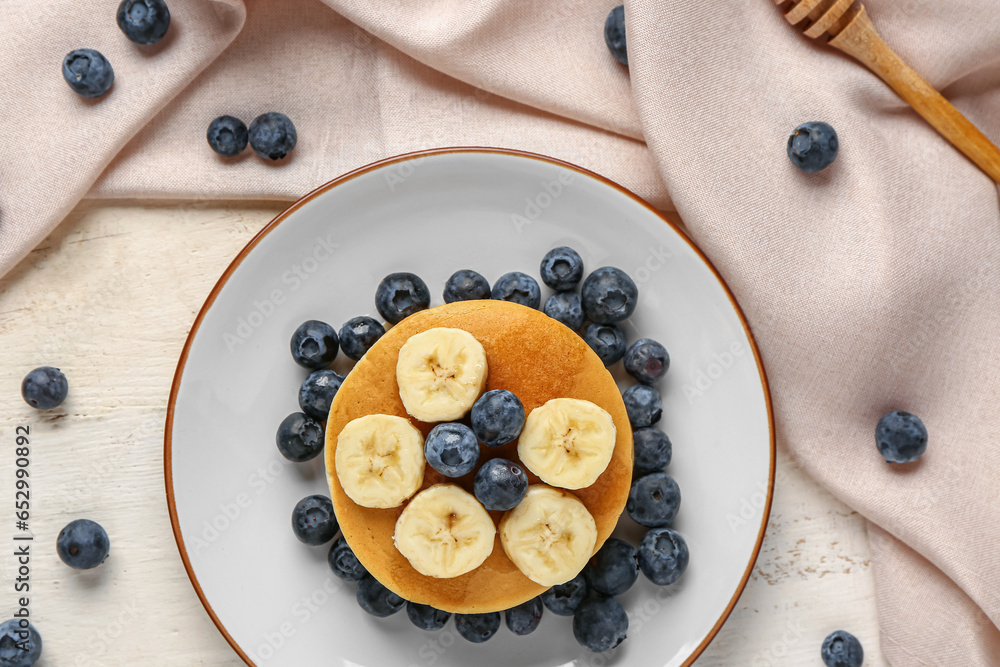 Plate with sweet pancakes, banana and blueberry on light wooden background