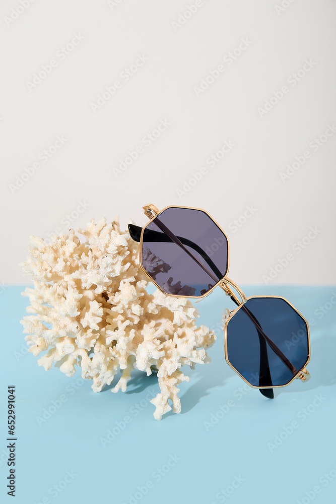 Coral with stylish sunglasses on blue table