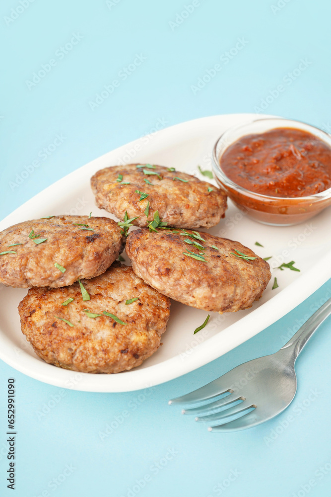 Cutlets with chopped parsley, ketchup and fork on blue background