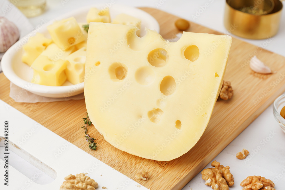 Board and plate with pieces of Swiss cheese on white table