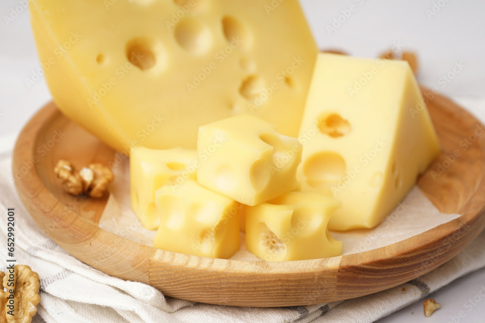 Plate with pieces of Swiss cheese and walnut on white background