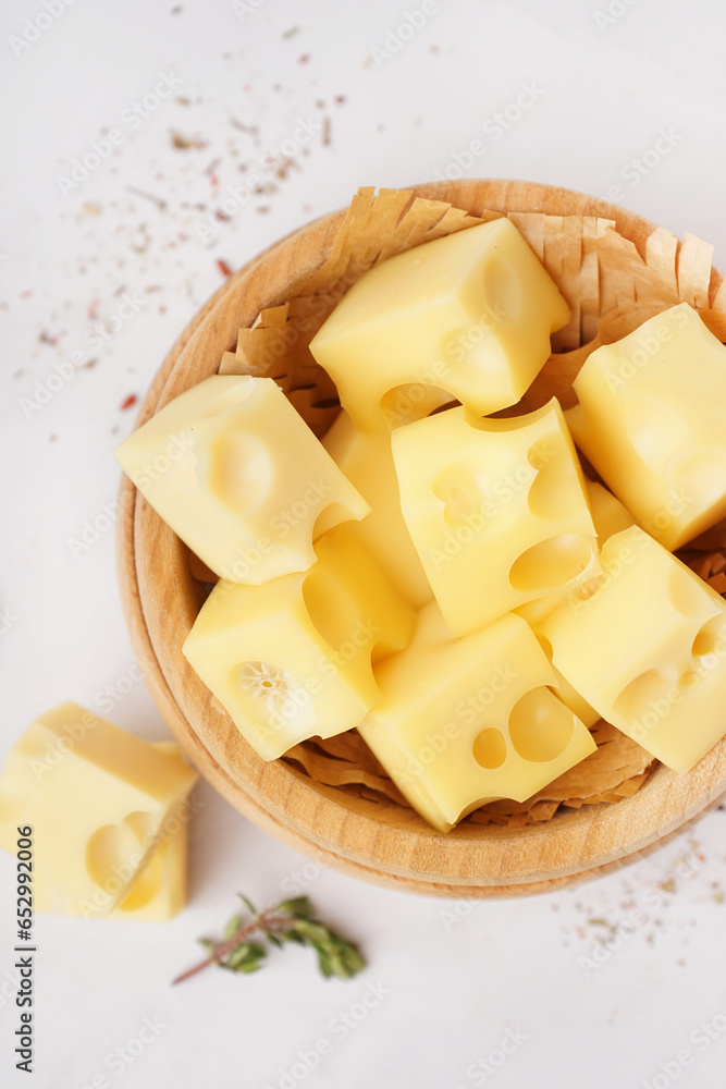 Bowl with pieces of Swiss cheese on white background