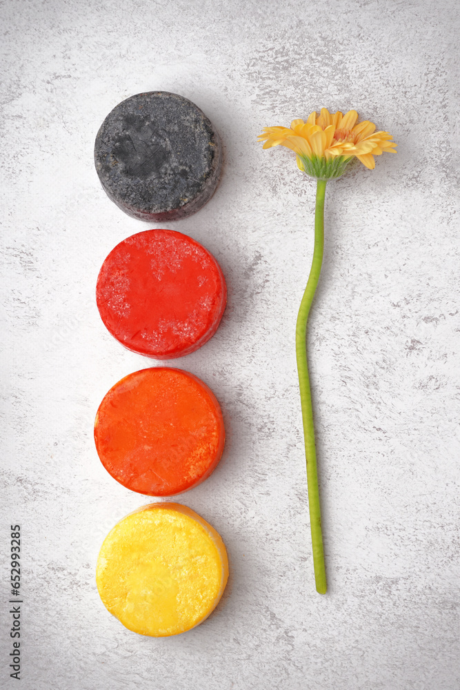 Different handmade solid shampoo and calendula flower on light background