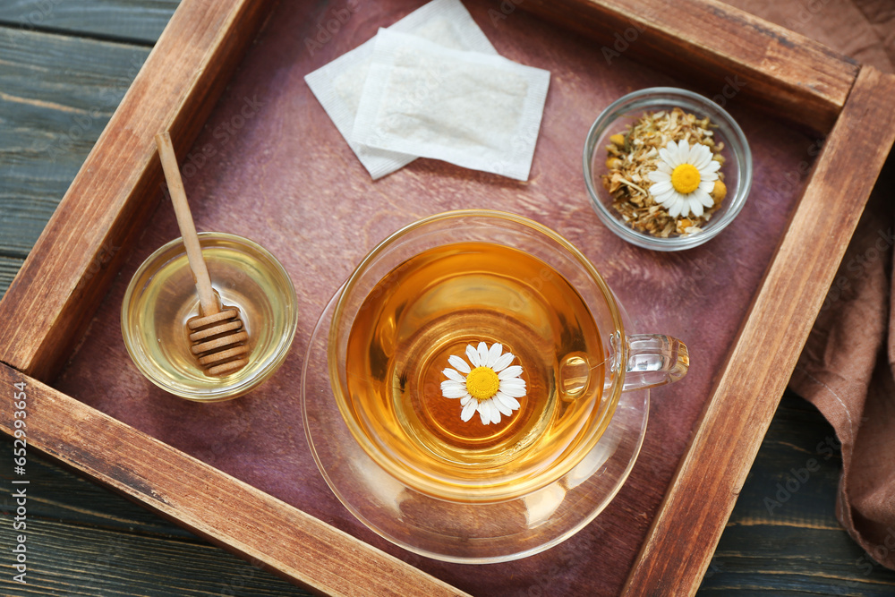 Cup of hot chamomile tea and honey on dark wooden background