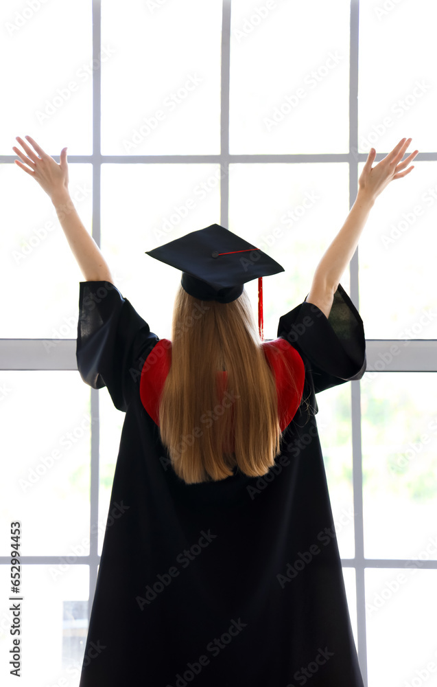 Female graduate student near window in room, back view