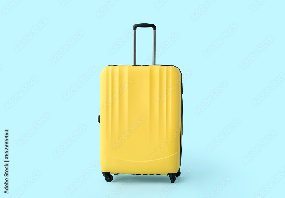 Yellow suitcase on blue background. Travel concept