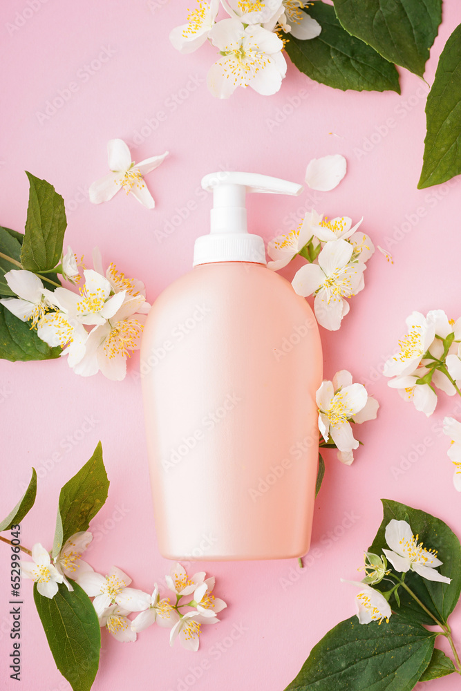 Composition with bottle of cosmetic product and jasmine flowers on pink background