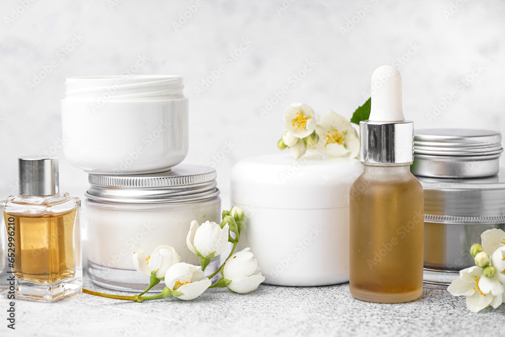 Set of different cosmetic products and beautiful jasmine flowers on light background