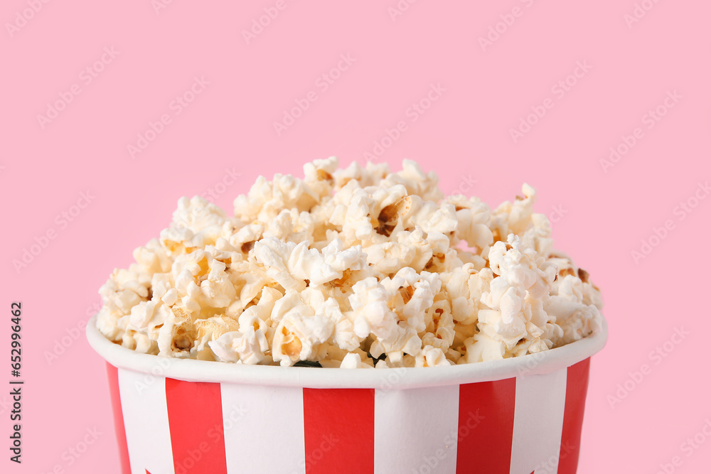 Bucket with tasty popcorn on pink background, closeup