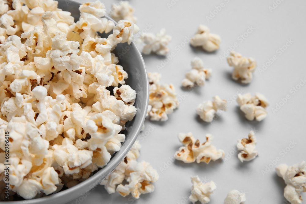 Bowl with tasty popcorn on grey background