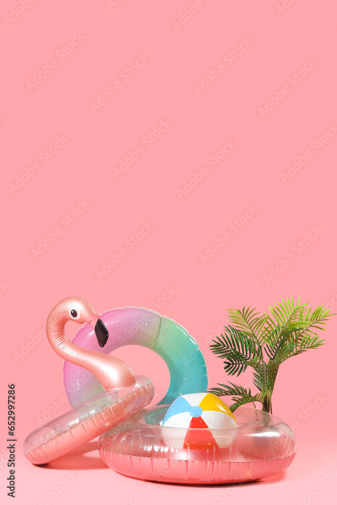 Different inflatable rings with ball and plant on pink background. Travel concept