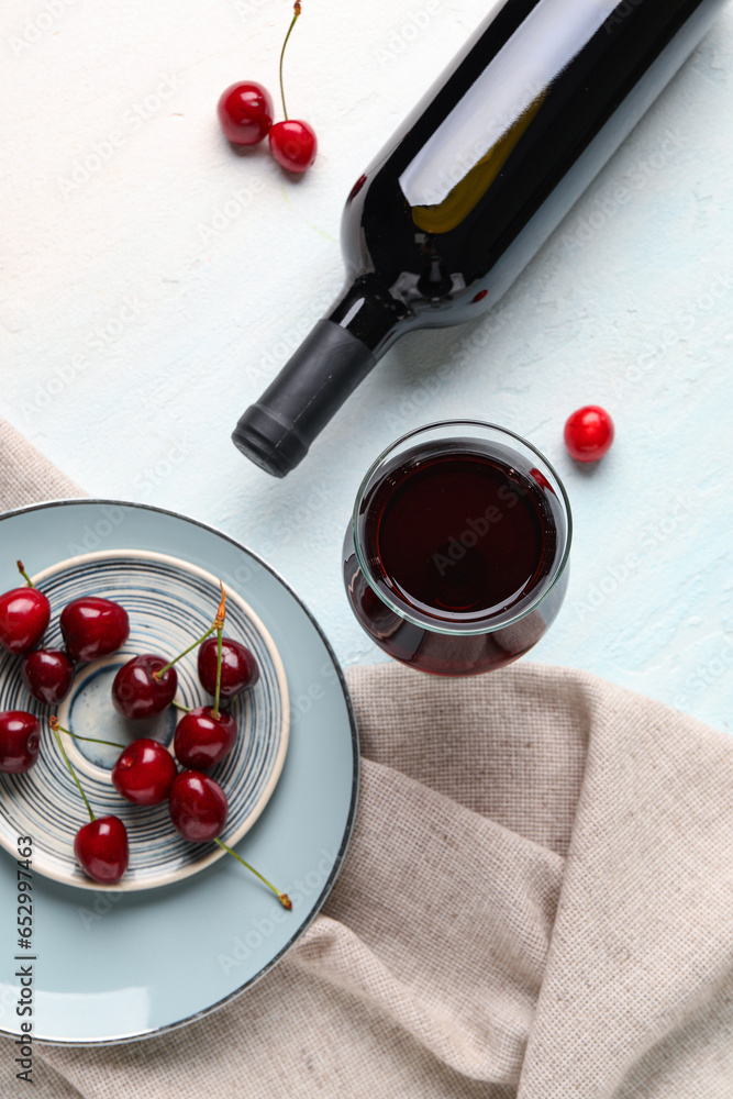 Bottle and glass of sweet cherry liqueur with berries on blue background