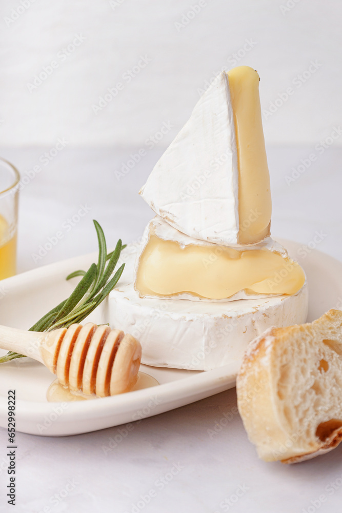 Plate with tasty Camembert cheese on light background