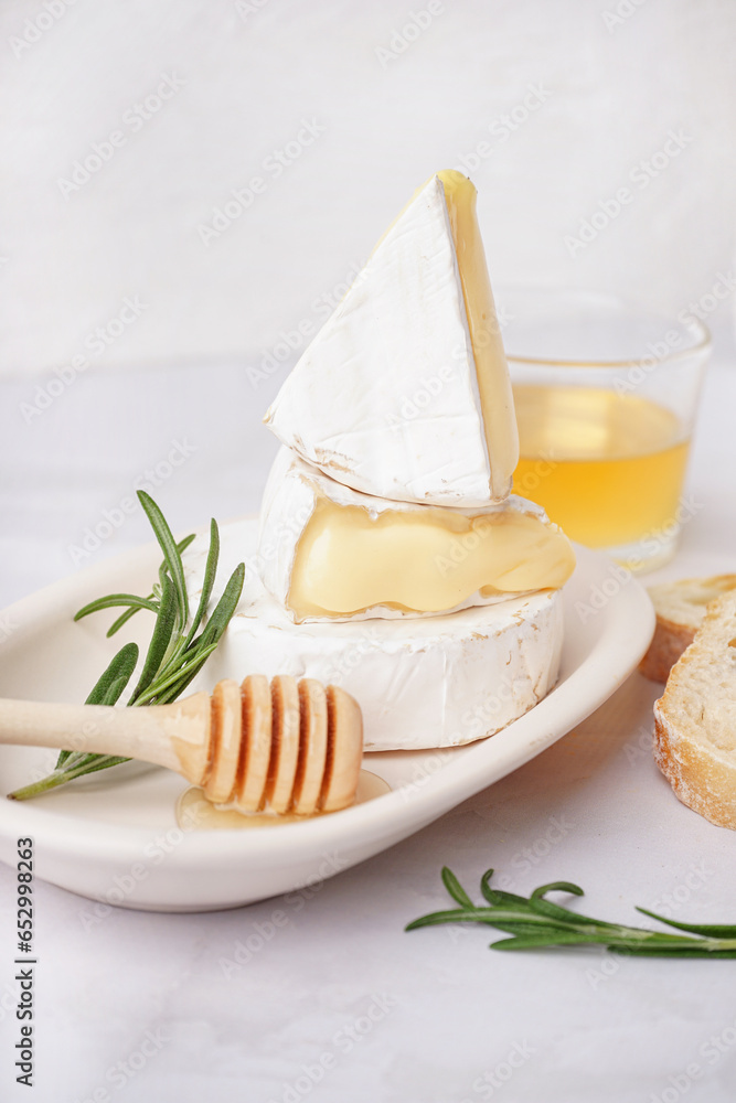 Plate with tasty Camembert cheese on light background