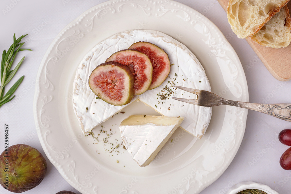 Plate with pieces of tasty Camembert cheese on grey background