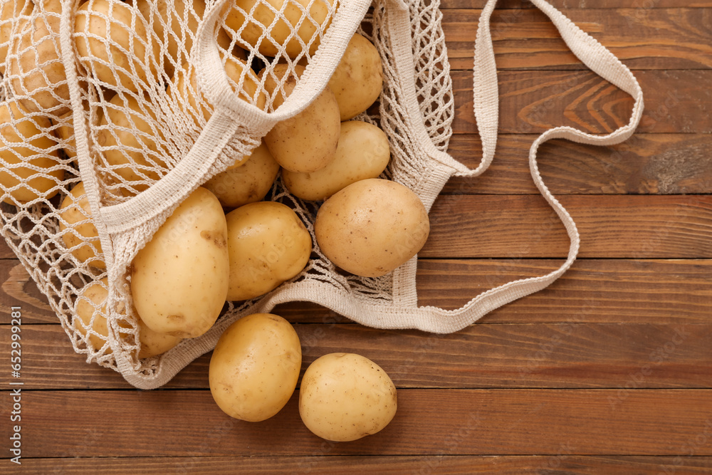 String bag with raw potatoes on wooden background