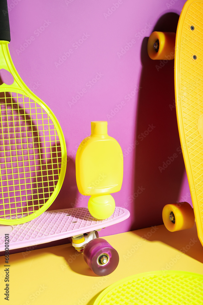 Composition with bottle of sunscreen cream, skateboards, tennis rackets and ball on color background