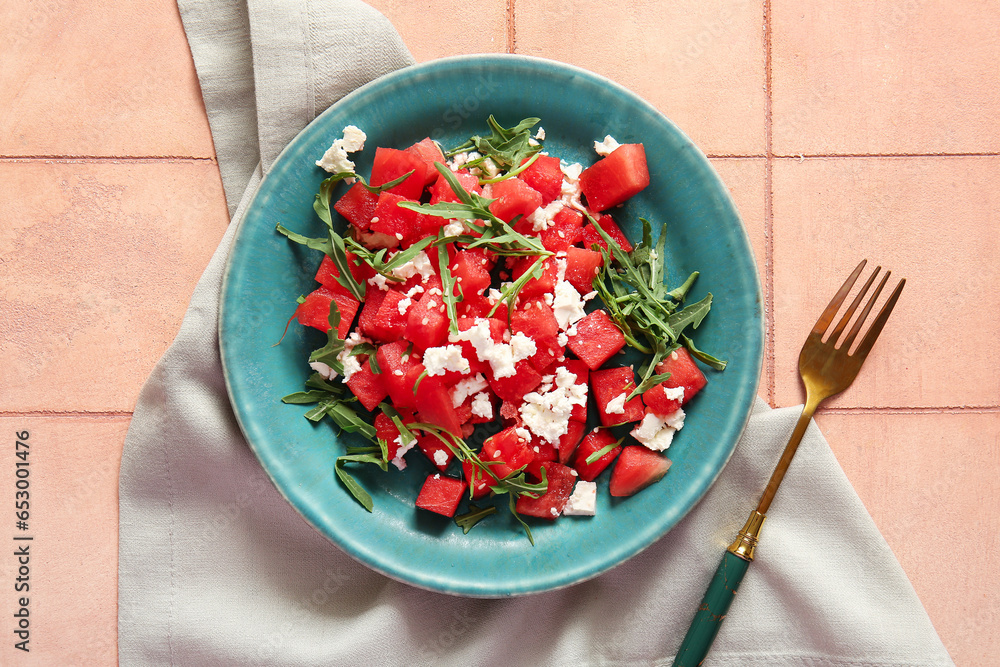 Plate of tasty watermelon salad on beige tile background