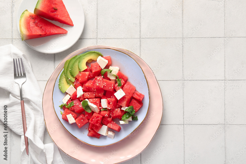 Plate of tasty watermelon salad on white tile background