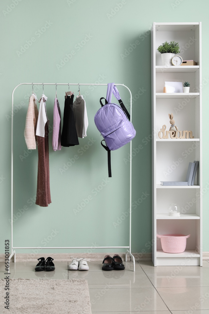 Stylish school uniform and backpack hanging on rack in childrens room