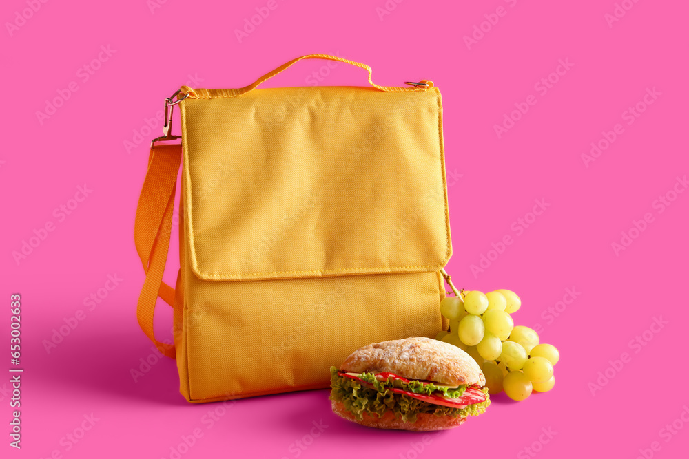 Lunch box bag with sandwich and grapes on pink background