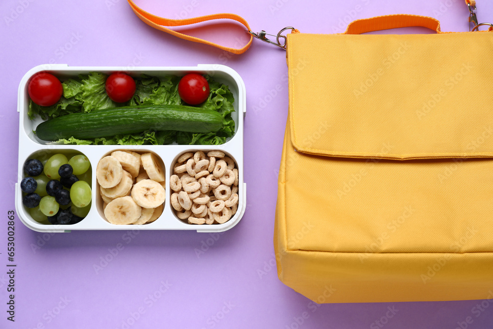 Bag and lunchbox with tasty food on lilac background