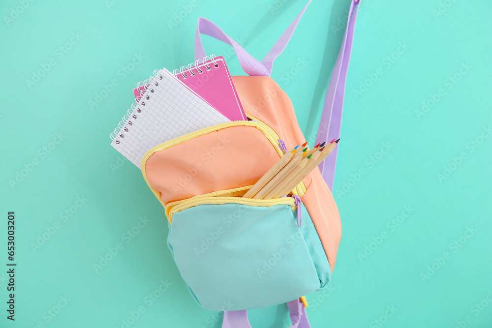 Color school backpack with stationery on turquoise background