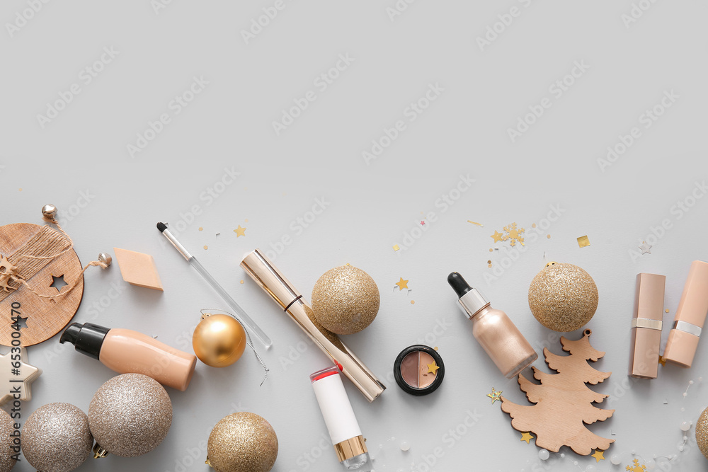 Composition with decorative cosmetics and Christmas decor on grey background