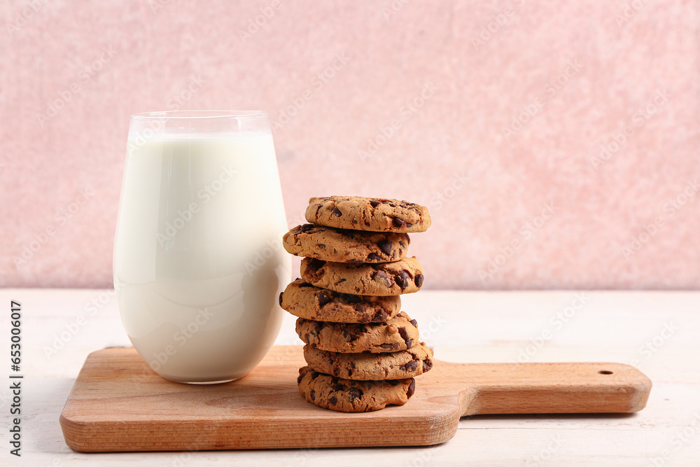 Glass of milk and tasty cookies with chocolate chips on table