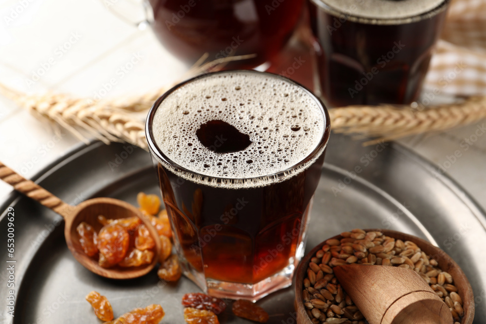 Glass of tasty kvass, raisins and wheat grains on table