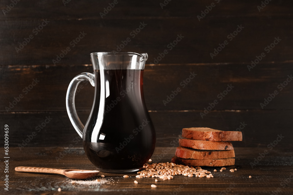 Jug of tasty kvass and ingredients on wooden background