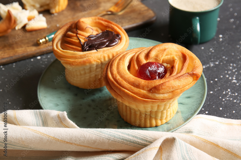 Plate of tasty cruffins with chocolate and jam on black background