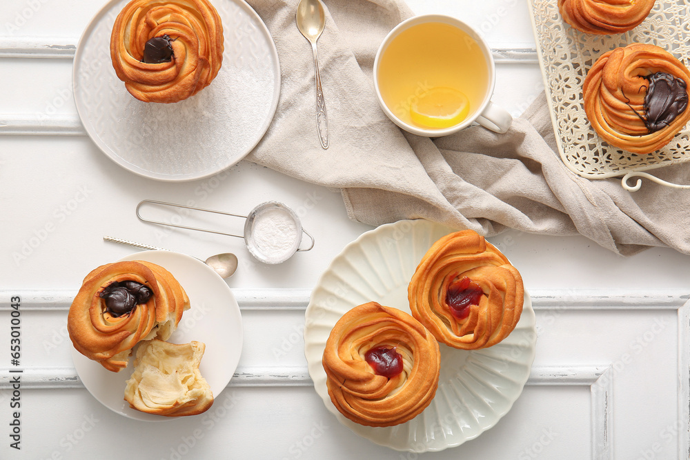 Tasty cruffins and cup of tea on white wooden background