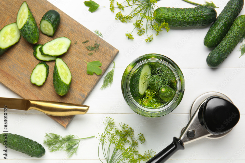 Jar with fresh cucumbers and ingredients for canning on white wooden background