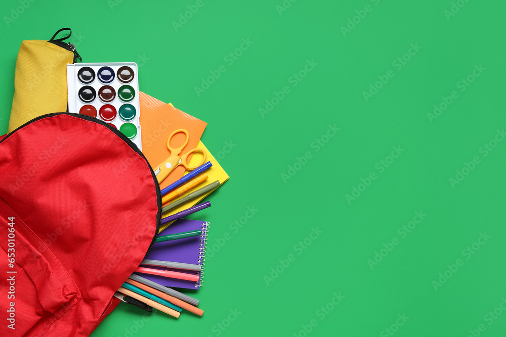 Stylish school backpack and different stationery on green background