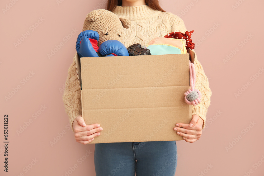 Woman holding box of unwanted stuff for yard sale on beige background