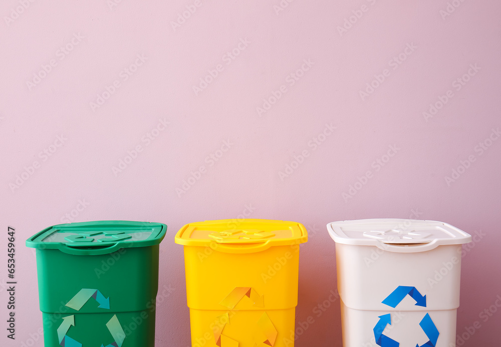 Garbage bins with recycling symbol near pink wall