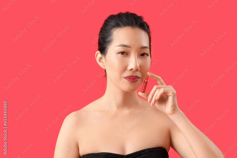 Beautiful Asian woman with ampule on red background. Skin care concept