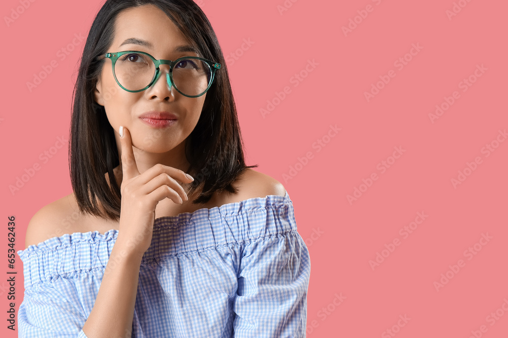 Thoughtful Asian woman in stylish eyeglasses on pink background, closeup