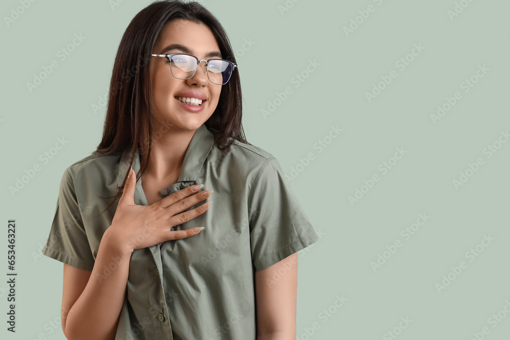 Beautiful young woman wearing glasses on color background