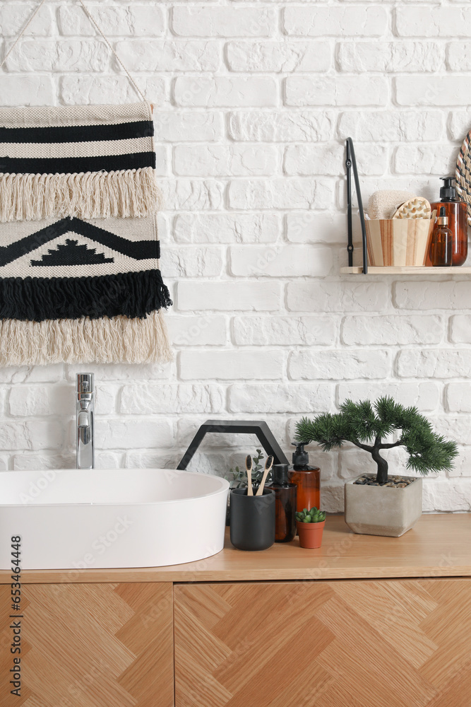 Sink bowl, bath accessories and bonsai tree on wooden cabinet in bathroom