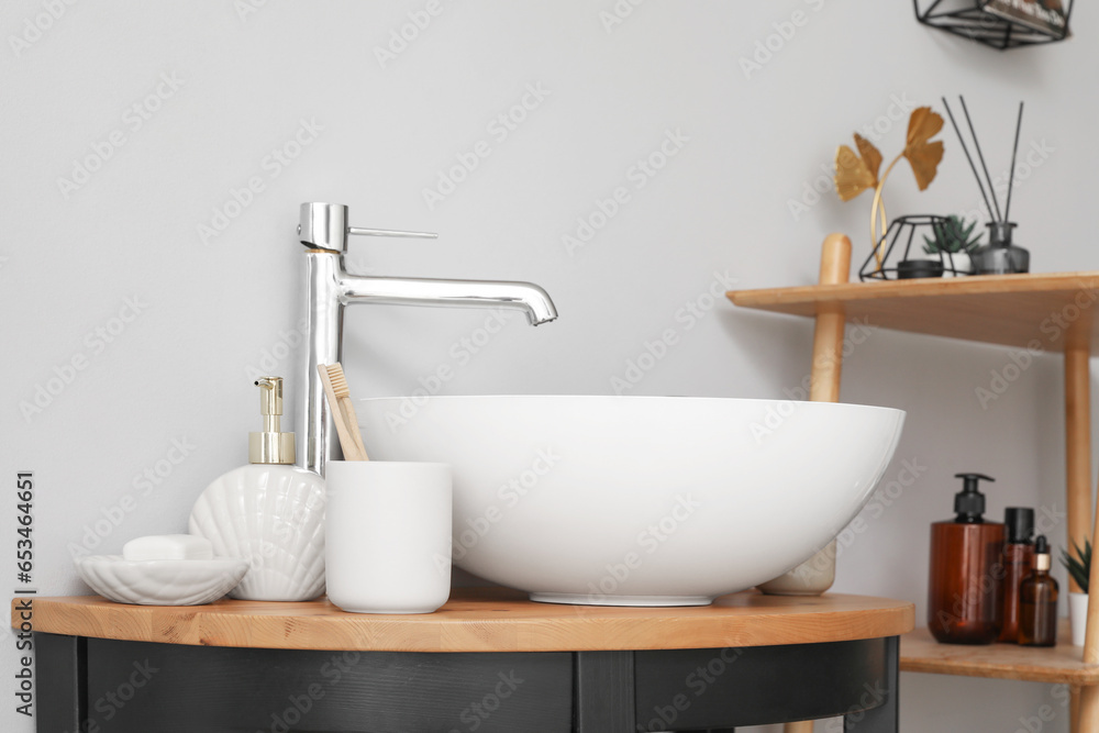 Sink bowl and bath accessories on table in bathroom, closeup