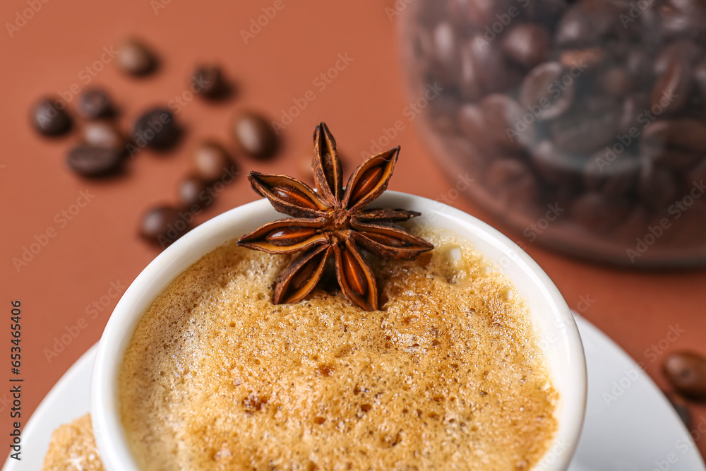 Cup of hot espresso and jar with coffee beans on brown background