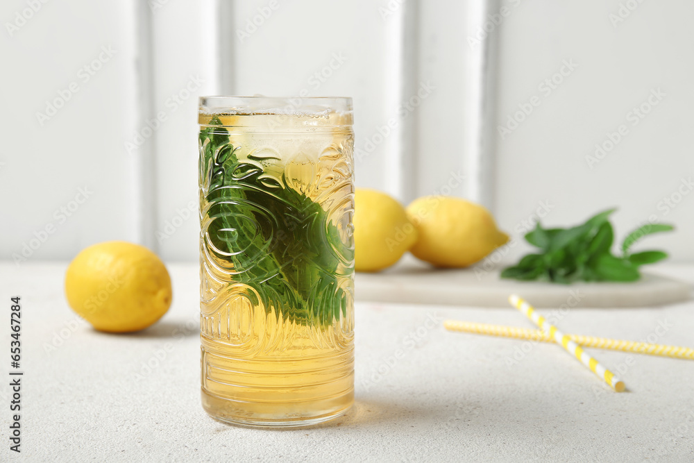 Glass of ice tea and board with lemons on white background