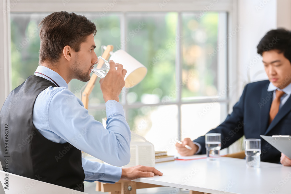 Male applicant drinking water at job interview in office