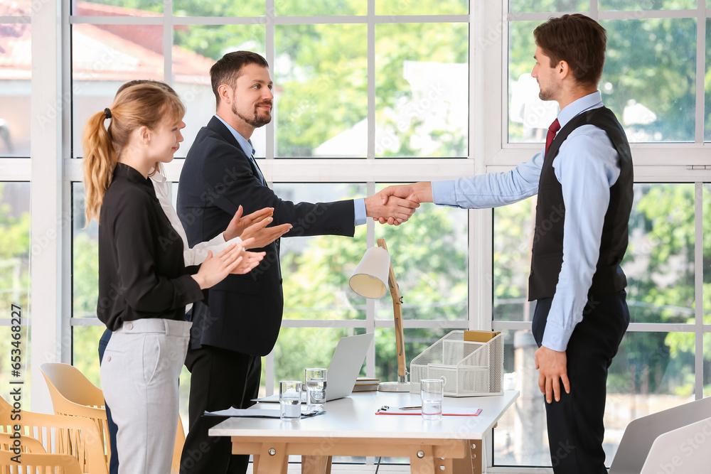 Human resources manager shaking hands with male applicant in office