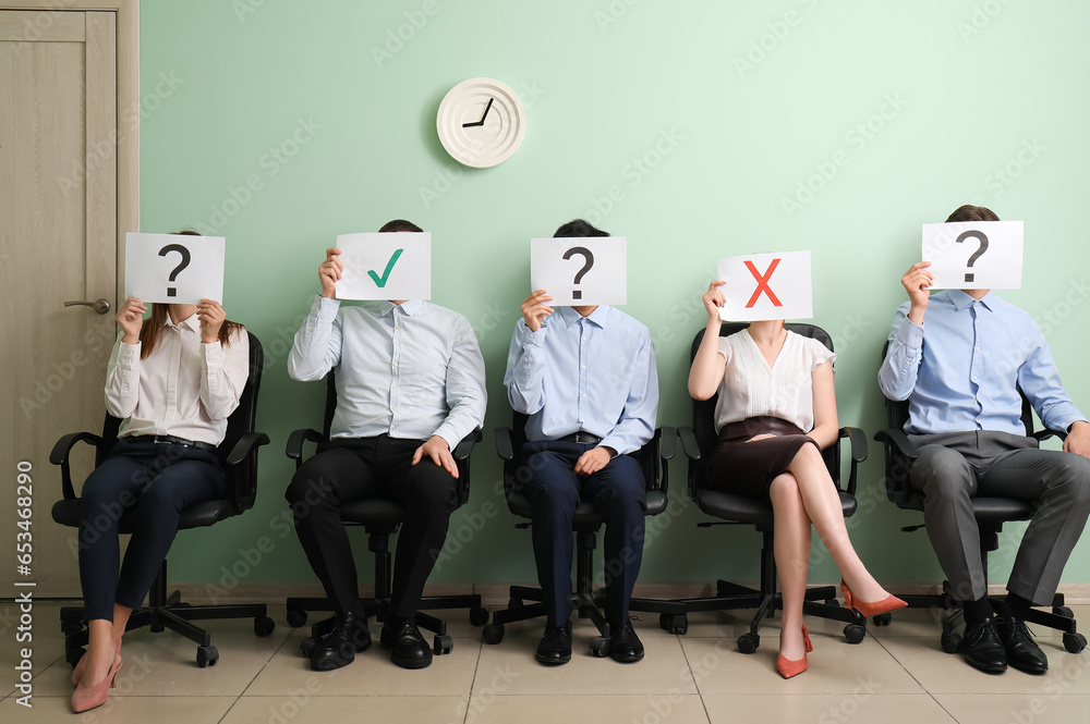 Young applicants holding paper sheets with different marks in room