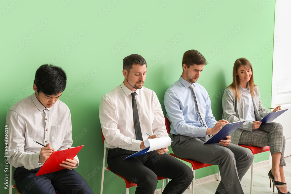 Young applicants with clipboards waiting for job interview in room